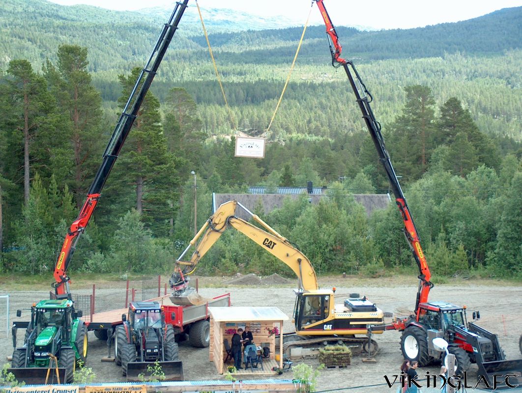 To kraner løfter tømmerstokker på plass under reising av lafteverk i Oppdal
